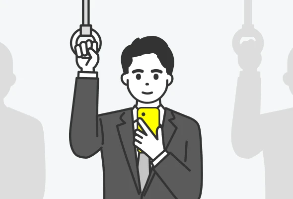 電車のつり革につかまりながらスマートフォンを見る人